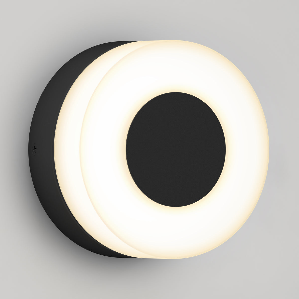 The Artika Ludwig modern LED indoor-outdoor wall light 5CCT features a black circular center with a glowing white ring, creating a sleek, contemporary look when mounted on a light gray wall.