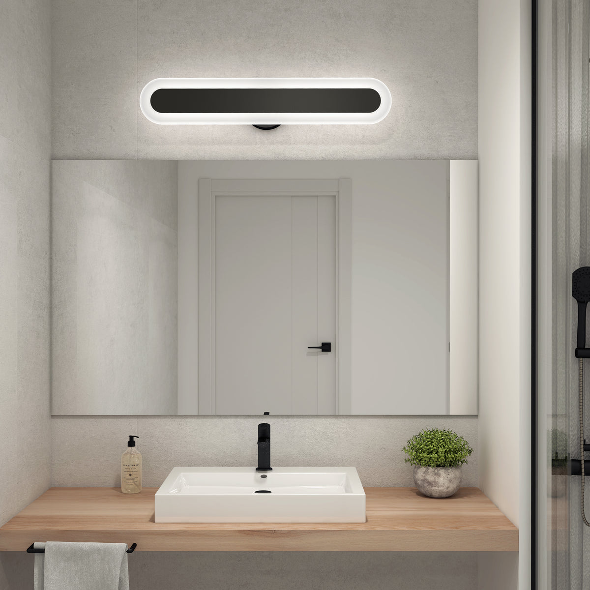 A modern bathroom features a rectangular mirror above a wooden countertop with a white sink, black faucet, soap dispenser, potted plant, and towel; an Artika Pista 27-in Integrated LED 5-CCT Vanity Light Bar is mounted above the mirror.