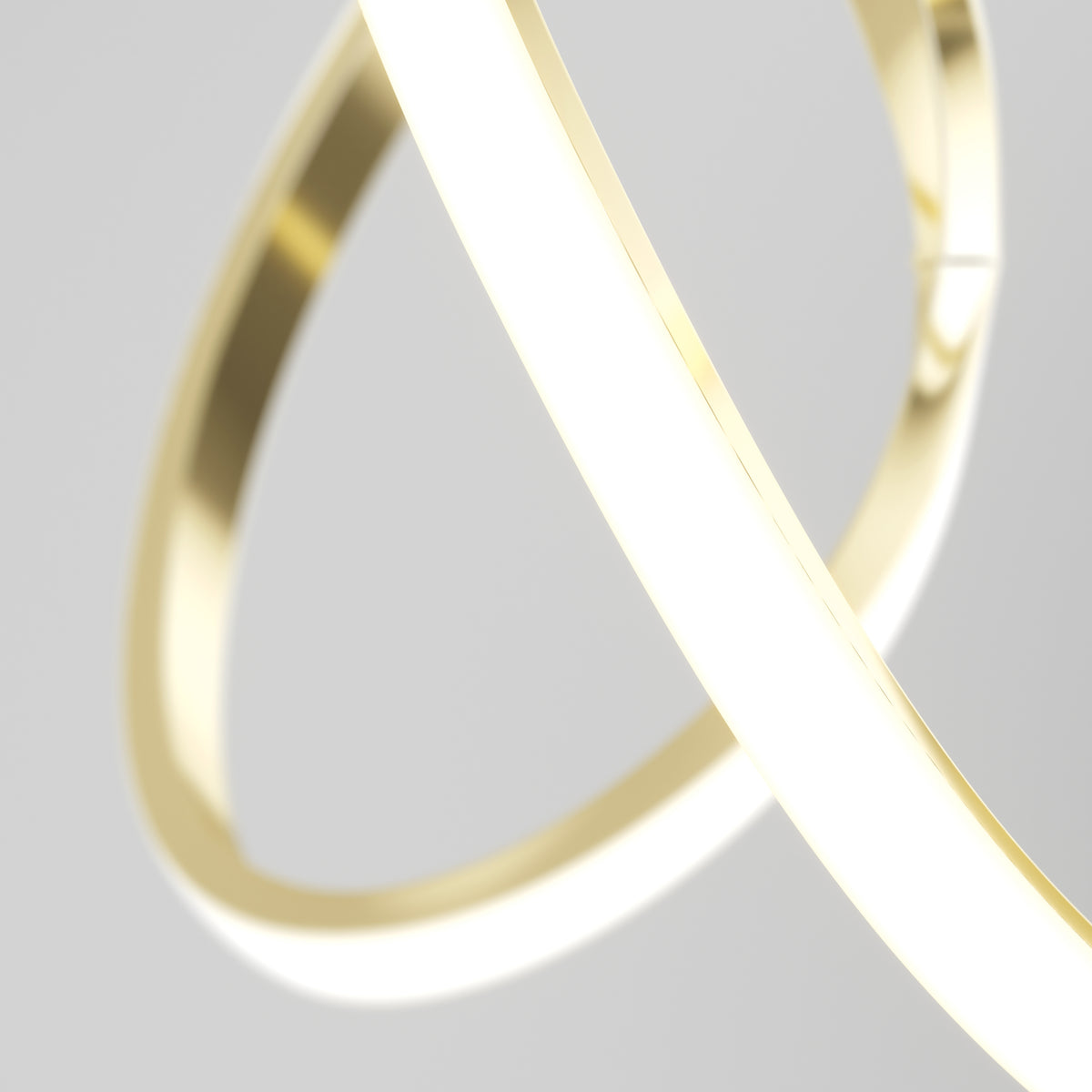 A close-up of two intertwined, glowing gold rings against a light gray background. The smooth, reflective rings belong to the Artika Swirl LED pendant light and showcase energy efficiency with a modern, abstract design.