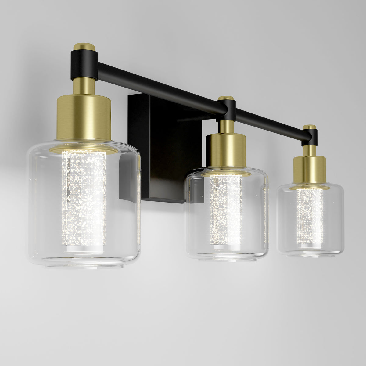 The Artika Champagne Globe bathroom vanity light features gold accents, clear glass shades, and a black base on a white wall.