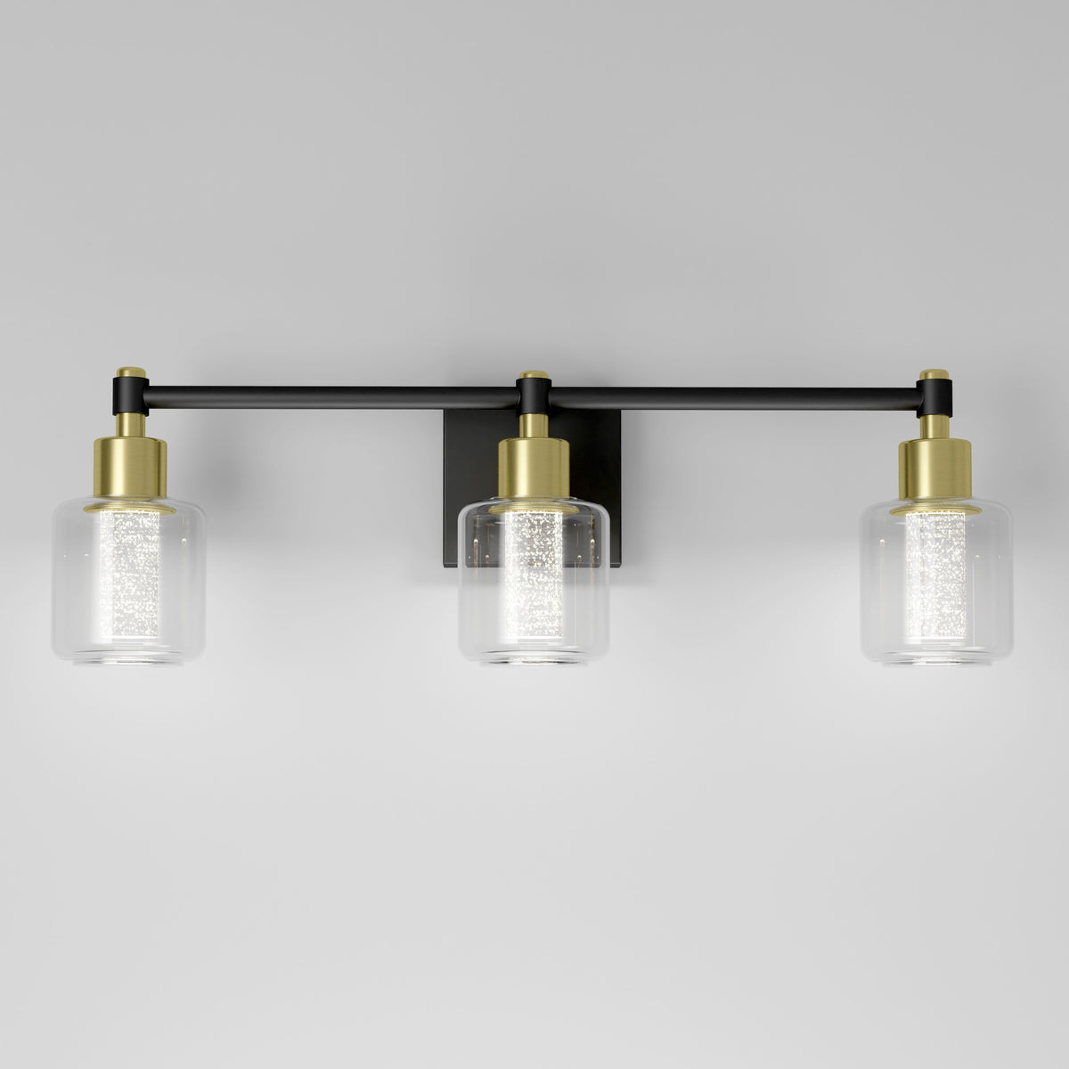 The Artika Champagne Globe vanity light features three clear glass shades, gold accents, and a black metal frame.