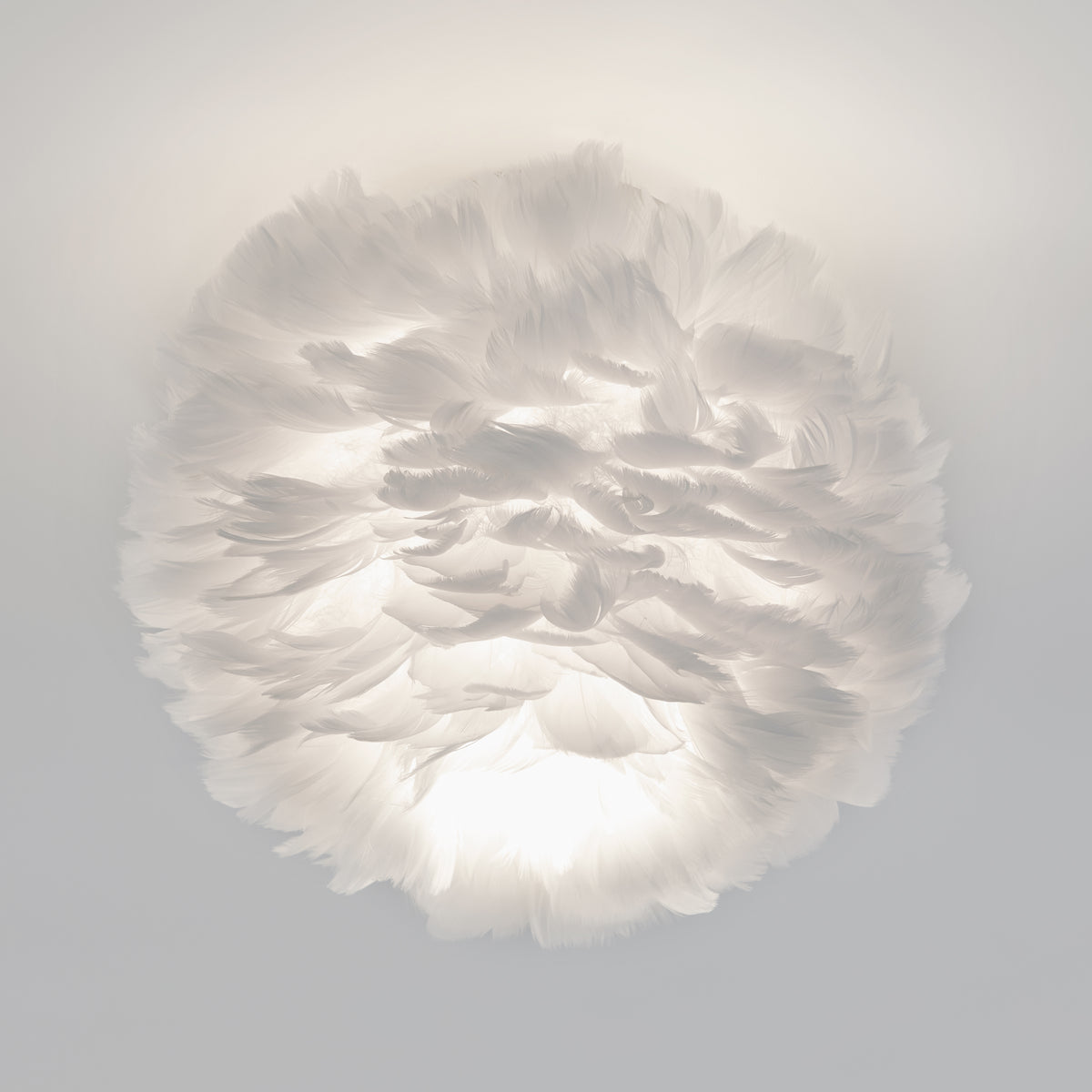 The Artika Plume LED flush mount light features a round design covered in soft white feathers, offering gentle, cloud-like illumination.