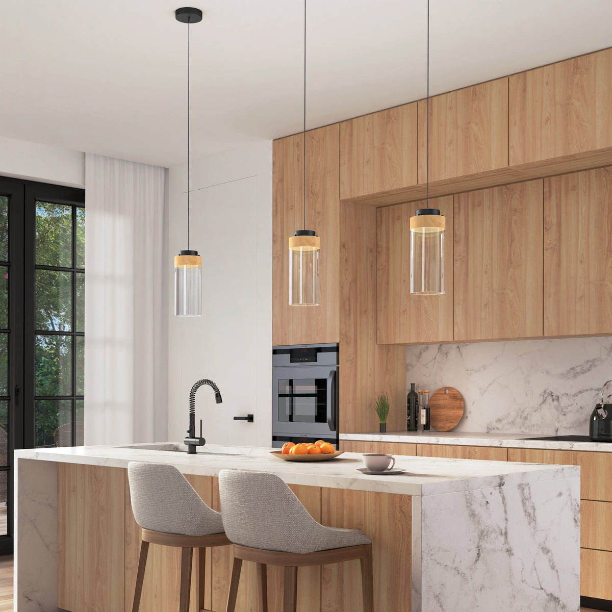 Modern kitchen with light wood cabinets, marble island and backsplash, two upholstered bar stools, a built-in oven, large windows overlooking greenery, and three Artika Hanson 1-light LED pendant 5 CCT lights above the island.