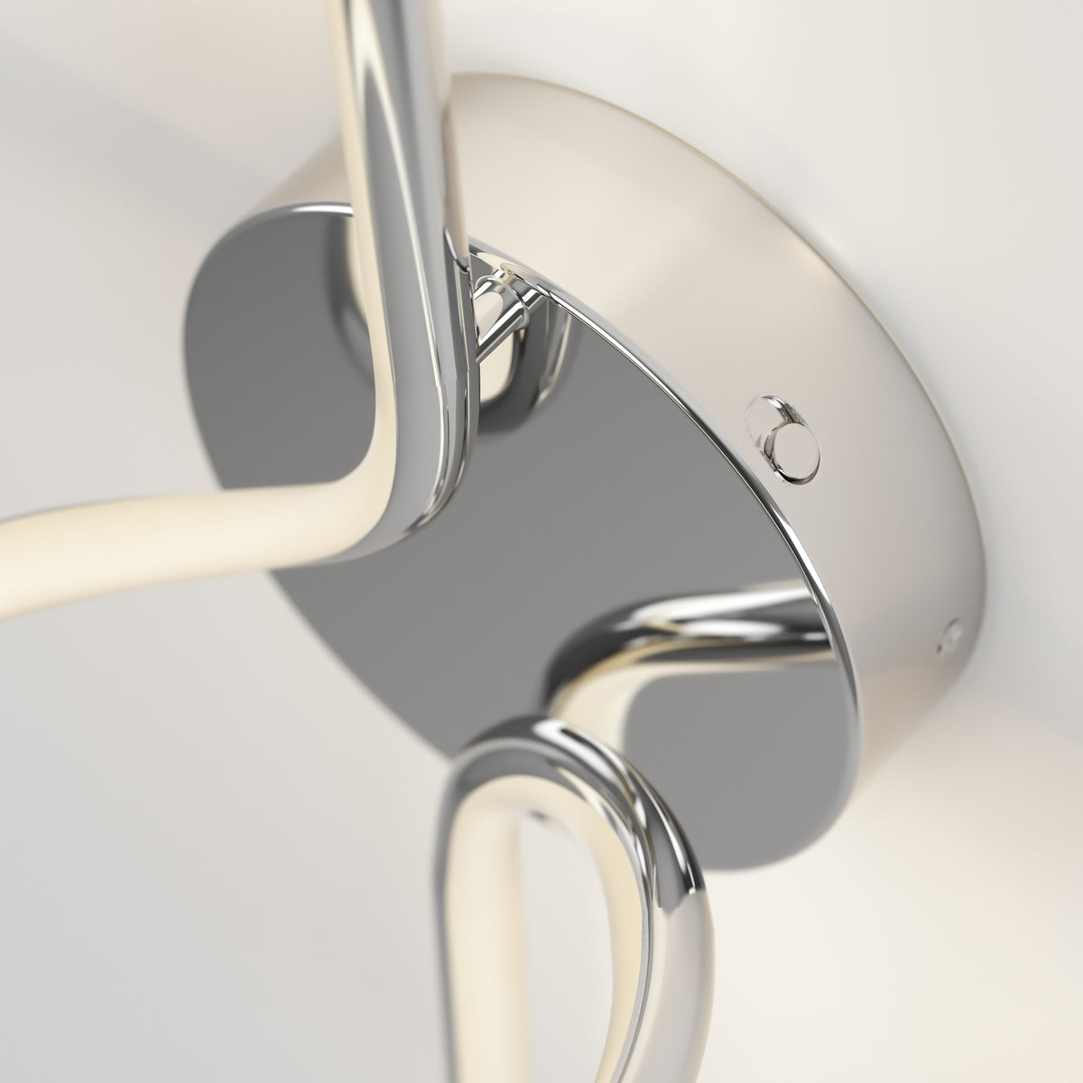 Close-up of Artikas Swirl LED Sconce: a sleek, contemporary wall fixture with a glossy chrome finish, circular base, and curved arms, adding modern style and reflective shine to any light-colored wall.