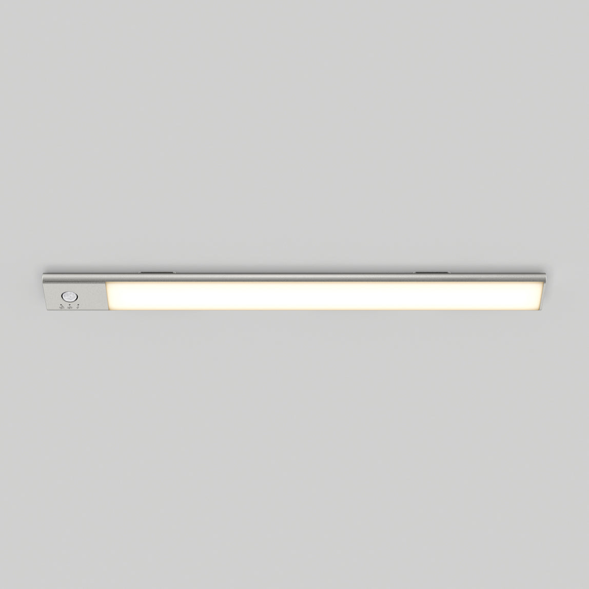 The Artika Outline under cabinet LED light 3CCT, a slim rectangular fixture, is mounted on a plain light gray ceiling. It emits a soft, even glow when turned on and features a small control button at one end.