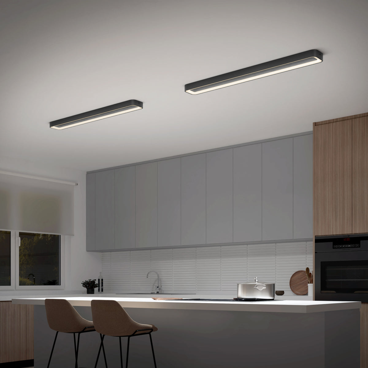 Modern kitchen featuring a white island, two brown chairs, wooden and grey cabinets, built-in oven, and two Artika Aiden 48 in. LED modern flush mount lights (5 CCT). Left wall has a window with a white blind.