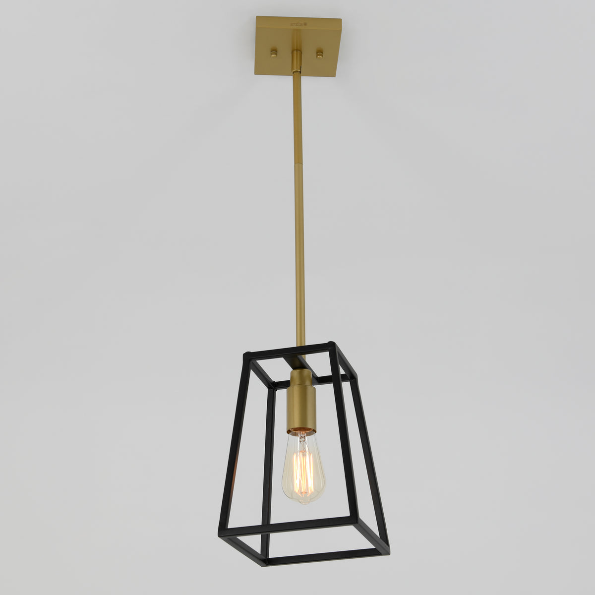 The Carter 1-light pendant by Artika features a gold rod and fixture, an exposed bulb, and a geometric black metal frame, suspended elegantly from a white ceiling.