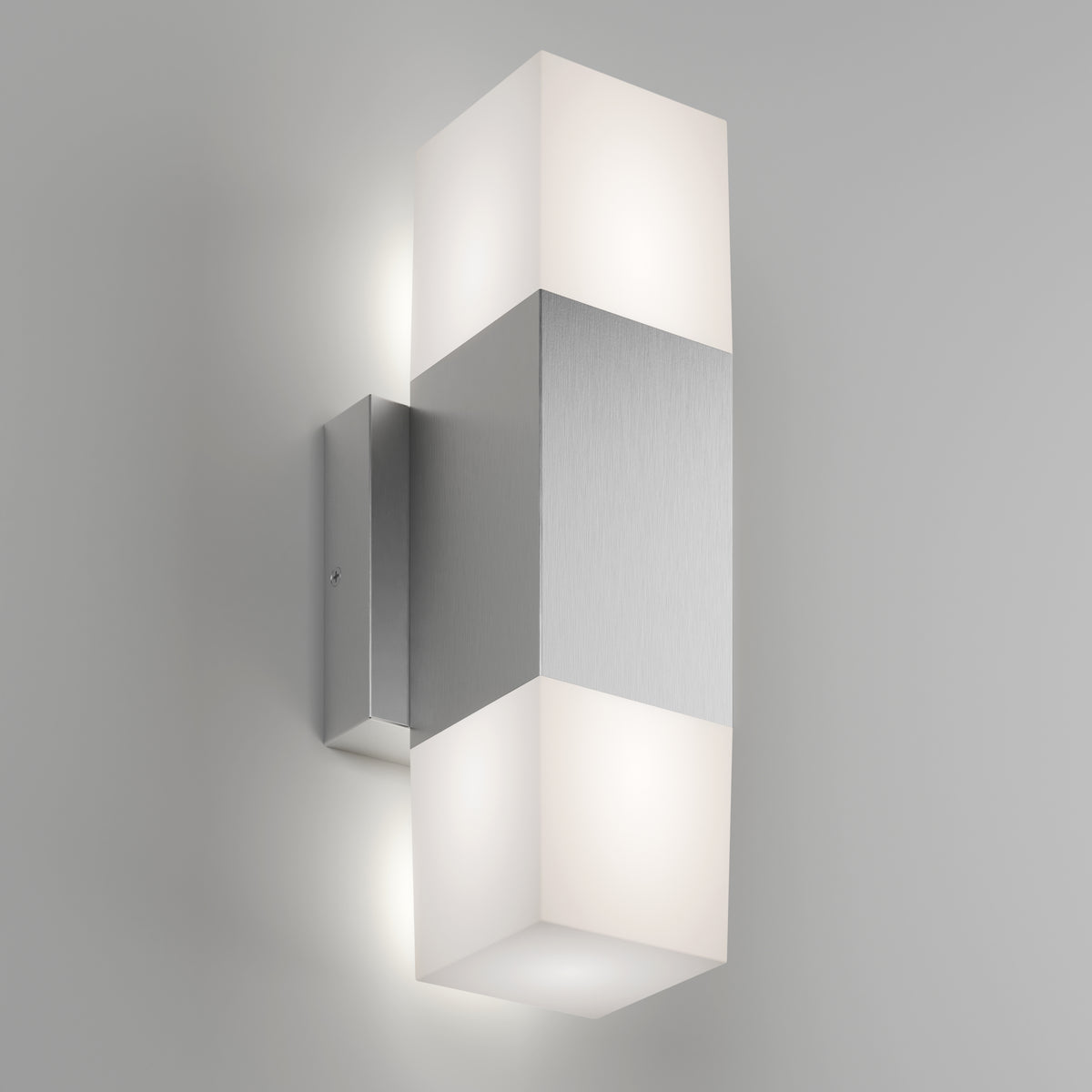 The Artika Lennox indoor-outdoor LED wall light 3 CCT features a brushed metal center and frosted rectangular diffusers that emit soft upward and downward light, shown mounted on a light gray wall.