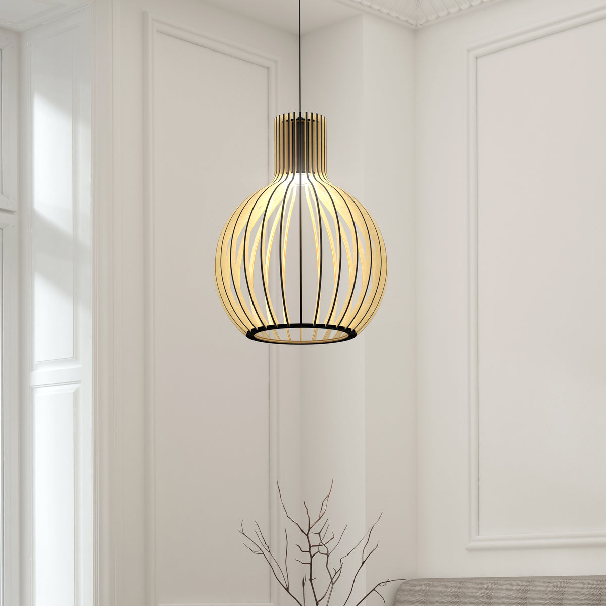 The Artika Tomi LED Pendant Light 3 CCT, featuring a modern black wireframe spherical design, hangs in a bright, minimalist room with white paneled walls and a tall window. A bare branch is visible in the foreground.