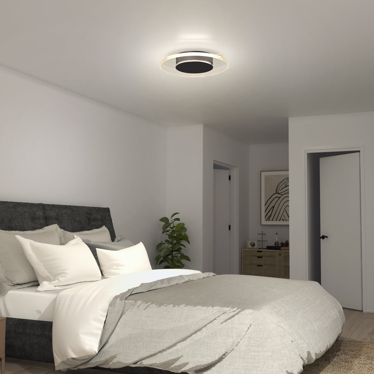 A modern bedroom features a gray upholstered bed, white and gray bedding, a small plant, a dresser with décor, and the Artika Essence Disk LED flush mount ceiling light. The walls and doors are painted white.