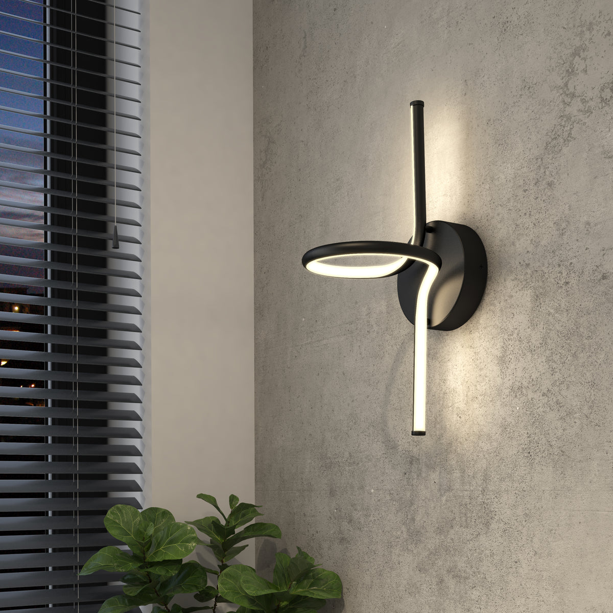 The Artika Swirl LED Sconce, a modern matte black fixture with circular and straight illuminated elements, features adjustable brightness and energy efficiency. It’s shown above a green plant on a gray wall near a window with blinds.