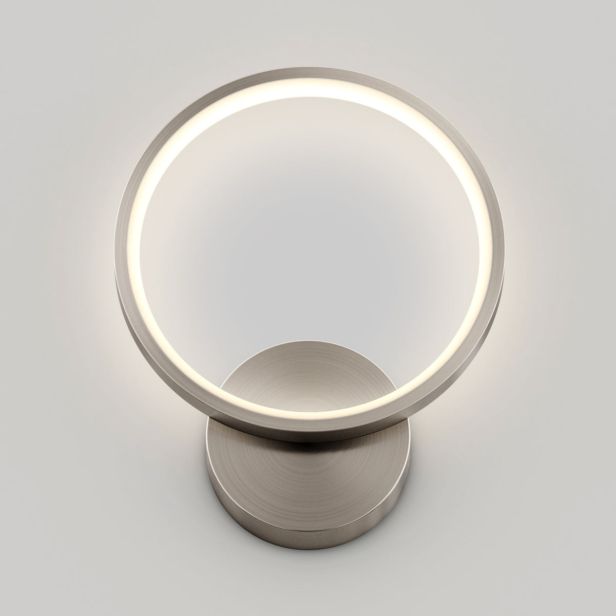The Artika Solis modern LED indoor-outdoor wall light 5 CCT features a sleek ring design and metallic base, perfect for accent lighting in contemporary spaces, shown against a plain light gray background.