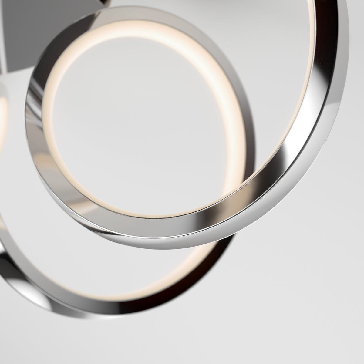 Close-up of the Swirl Ribbon LED pendant light by Artika, showcasing two intertwined chrome rings with integrated LEDs. The modern, minimalist design creates an elegant statement against a plain light gray background.