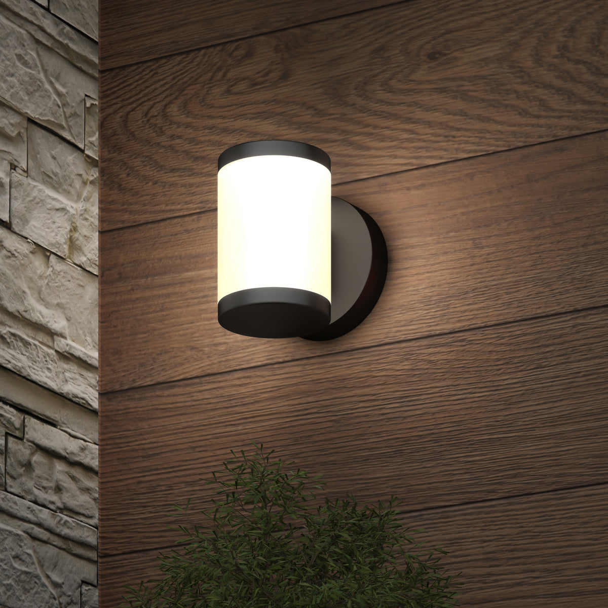 The Artika Landon LED Outdoor Wall Light 2-Pack brightens wood siding near stone, casting light on a leafy green plant below.