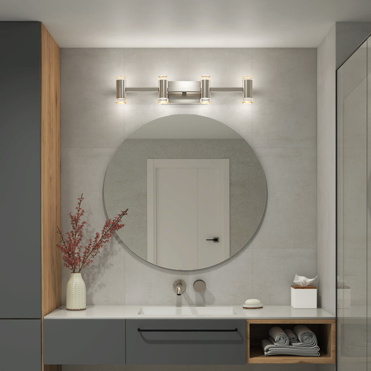 A modern bathroom features a round mirror above a white sink, gray cabinets, towels, and a vase with red branches. The Artika Mist modern LED bathroom vanity light 5 CCT provides sleek adjustable lighting reflected in the mirror.