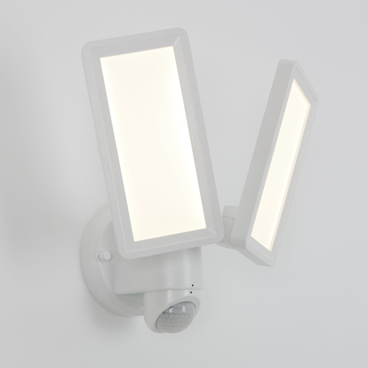 The Artika Sentinel outdoor Flat Panel Security light, a modern white dual-panel LED with motion sensor, is mounted on a white wall with both rectangular panels illuminated.