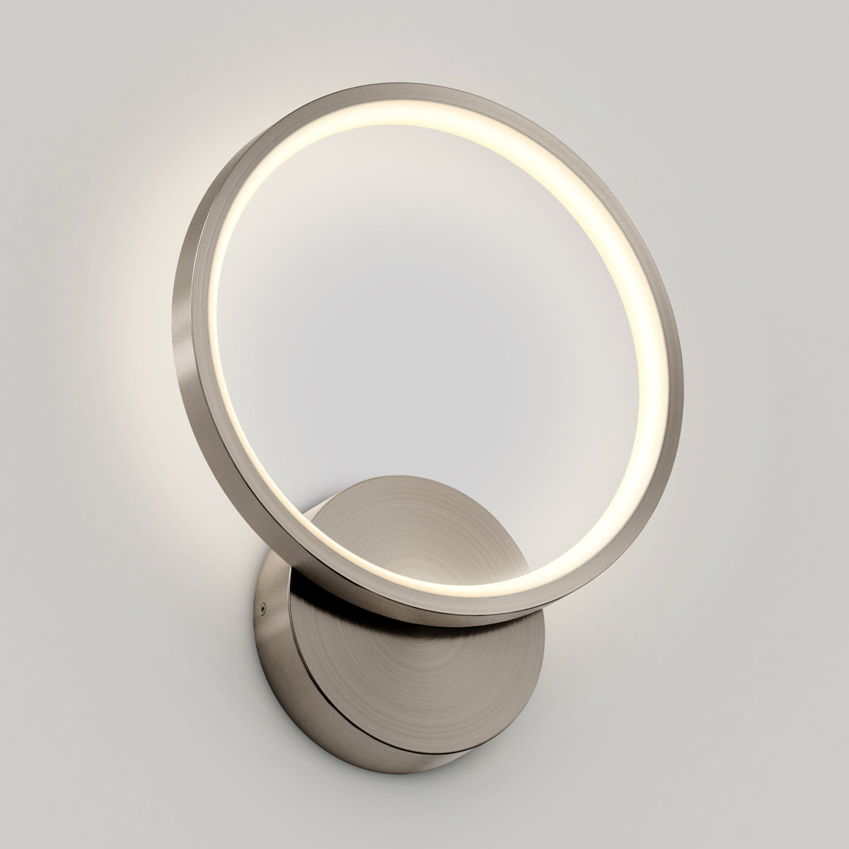 The Artika Solis modern LED indoor-outdoor wall light 5 CCT features a sleek circular ring and metallic base, casting a soft, warm glow—ideal accent lighting for contemporary spaces.