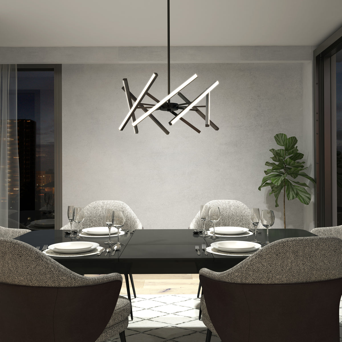A modern dining room with a black table for four, gray upholstered chairs, an Artika Malibu LED pendant light, a potted plant in the corner, large windows, and a neutral color palette.
