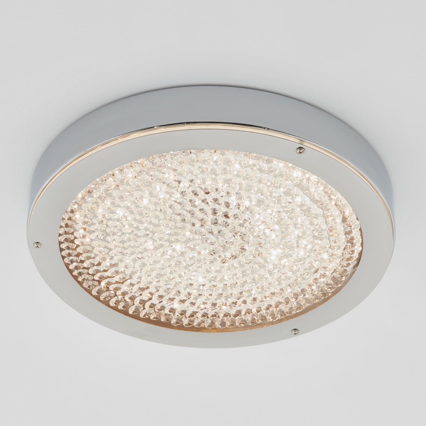 The Artika Glitter LED flush mount is a round, flush-mount ceiling light featuring a chrome frame and a textured, crystal-like surface that diffuses bright white light.