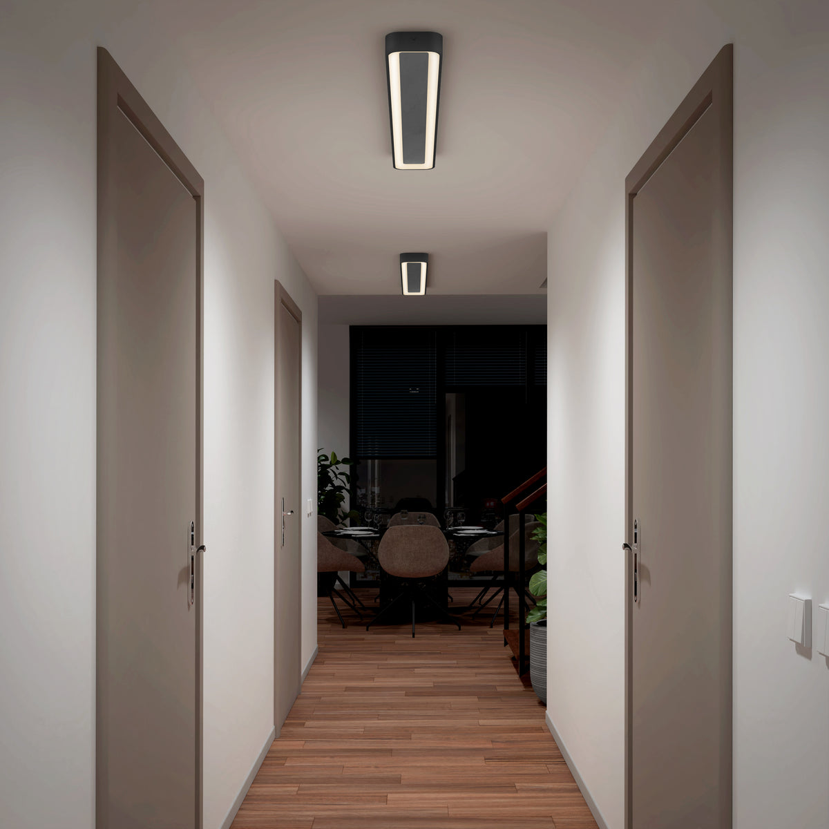 A hallway with wooden floors and white walls features the Artika Aiden 48 in. LED modern flush mount light 5 CCT on the ceiling, illuminating closed doors on both sides and a dining area with a table and chairs at the end.