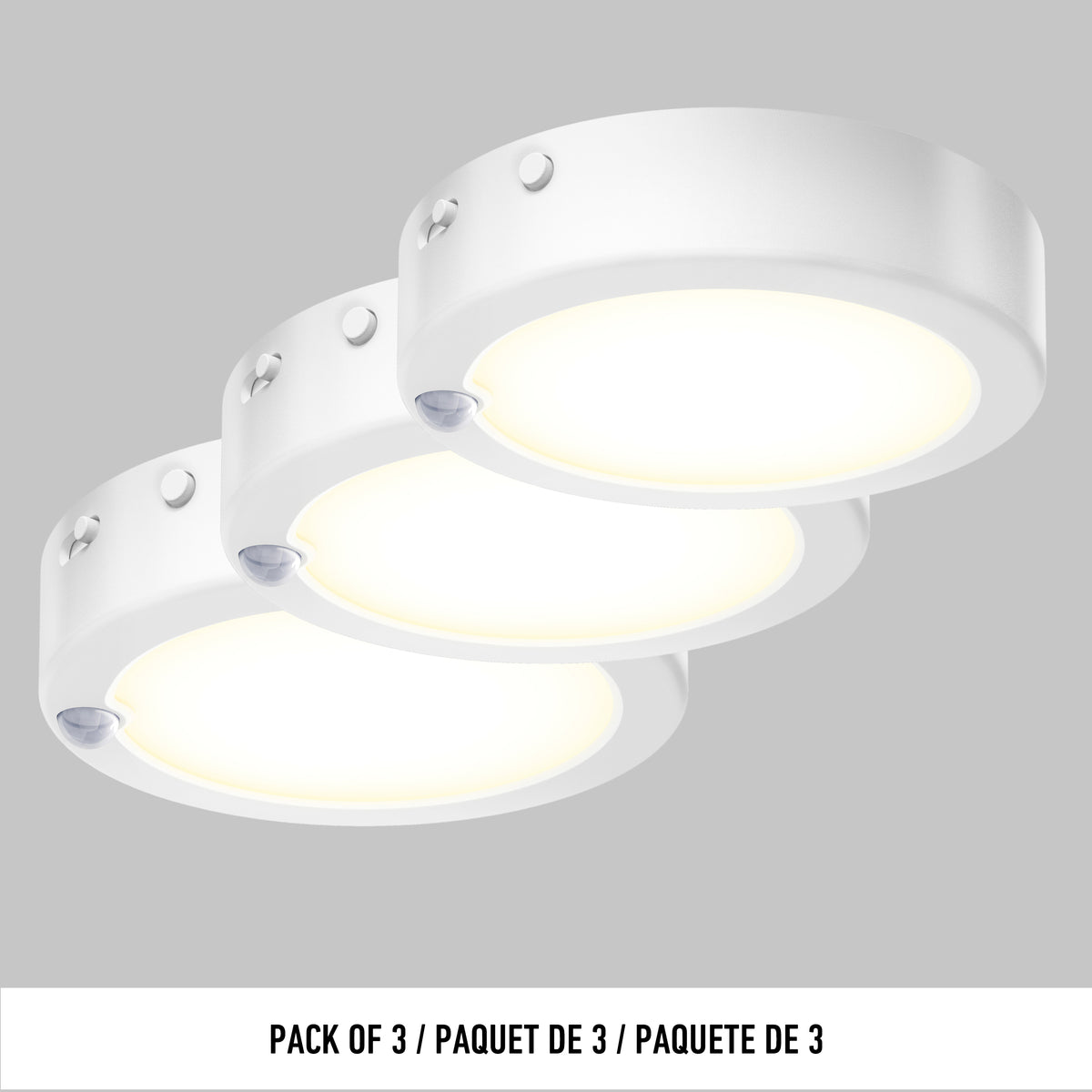 Three round, white Artika Accent under cabinet LED light 3CCT surface-mounted puck lights arranged in a row on a gray background. Text below reads: PACK OF 3 / PAQUET DE 3 / PAQUETE DE 3.