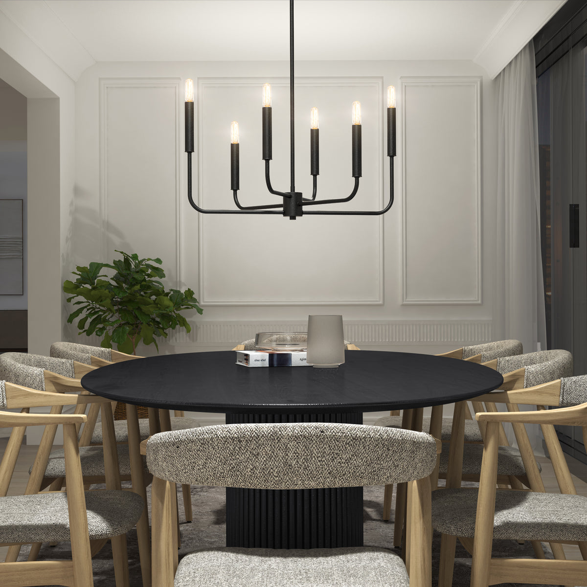 A modern dining room features a round black table, eight cushioned wooden chairs, light-colored walls with molding, a corner plant, and the Manchester 6-light pendant by Artika hanging above.