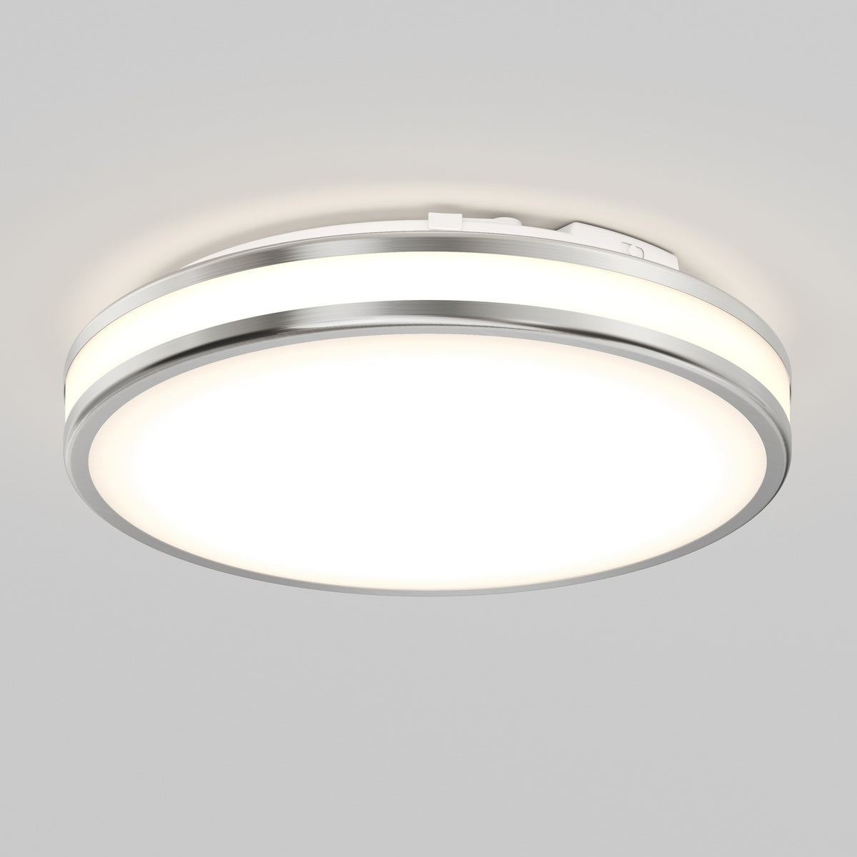 The Artika Hemisphere 15 in. LED flush mount light offers 5 CCT adjustable brightness with a modern round design, brushed metal rim, and frosted diffuser—ideal for stylish, functional bathroom lighting on a light gray ceiling.
