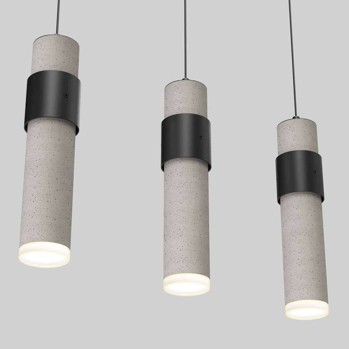 The Artika Barden 3-light LED pendant light features cylindrical concrete shades with black metal bands, suspended from black cords. Each light emits a soft white glow against a plain gray background.