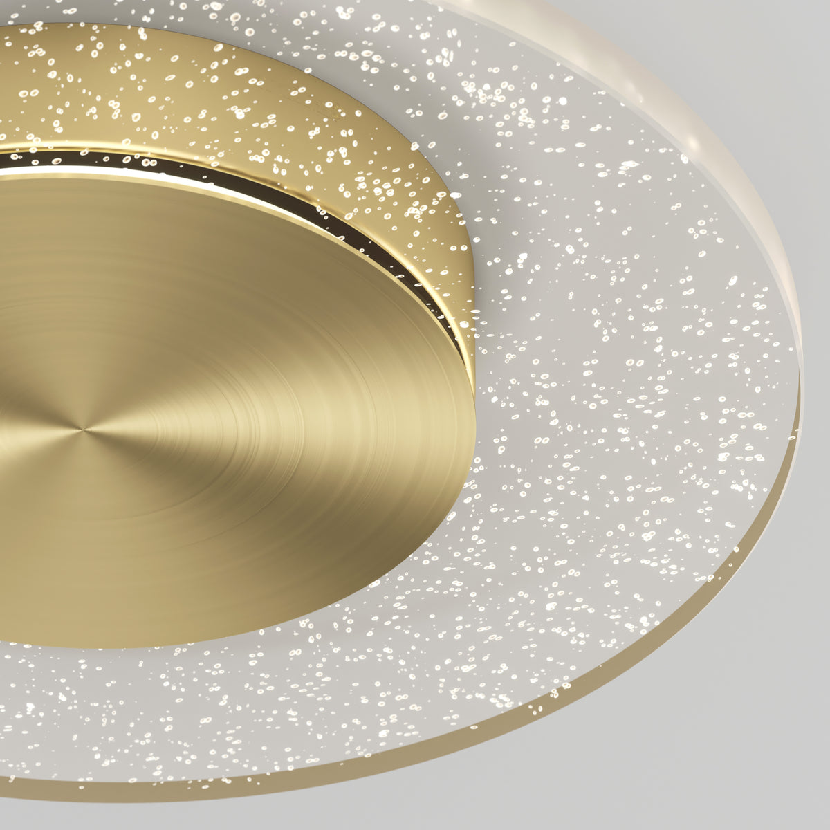 Close-up of the Artika Essence Disk LED flush mount, featuring a brushed gold center and a translucent ring with sparkling bubble-like dots that create a starry effect, set against a neutral light gray background.