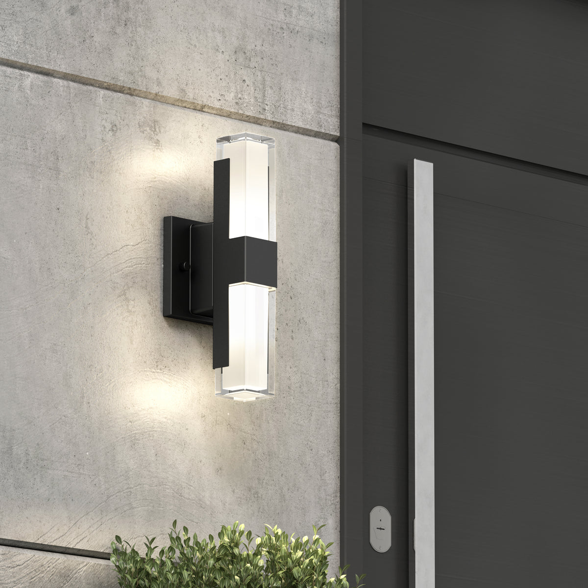 The Artika Gemini indoor-outdoor LED wall light, with matte black finish, frosted glass, and adjustable color temperature, is mounted on a gray concrete wall near a door and greenery—ideal for stylish lighting.