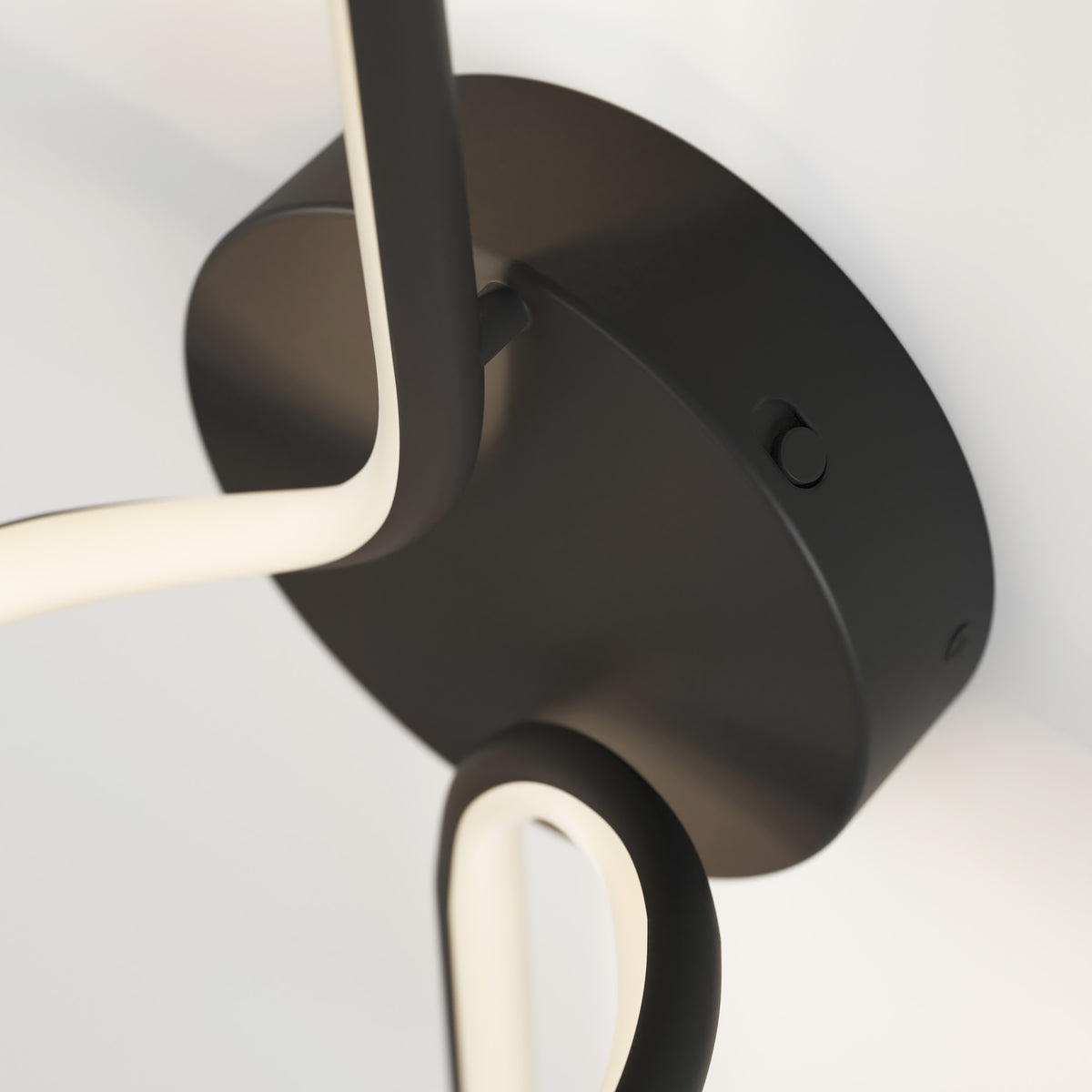 Close-up of Artika’s Swirl LED Sconce, a modern black ceiling light featuring elegantly curved, illuminated LED arms set against a white ceiling.
