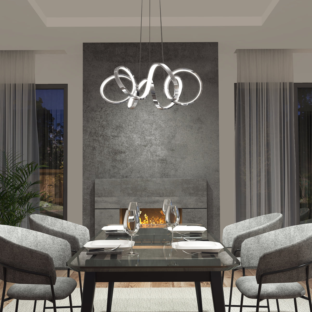 A modern dining room featuring a glass table for four, gray upholstered chairs, Artika’s Swirl Ribbon LED pendant light, a textured gray wall, fireplace, floor-to-ceiling windows with sheer curtains, and a potted plant.