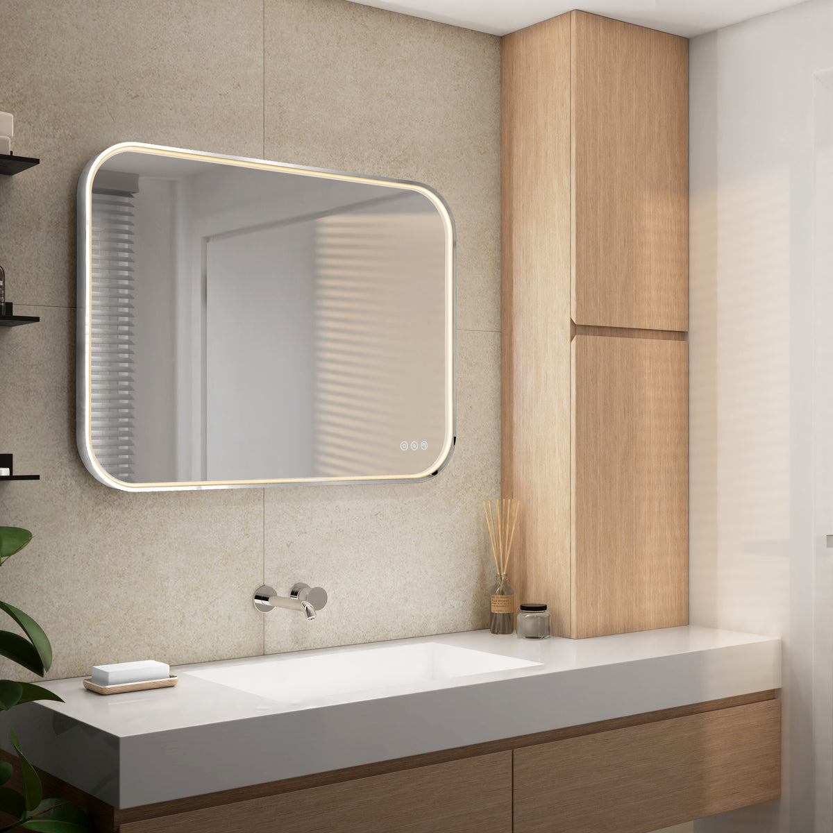 Modern bathroom with the Artika Royce Dimmable LED Mirror (3 CCT, horizontal/vertical mount) above a white sink, wall-mounted faucet, light wood cabinets, plant, and reed diffuser. Neutral tones and minimal decor.
