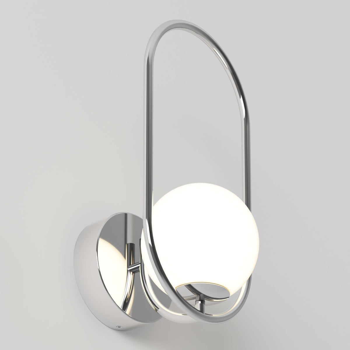 The Artika Bloom LED Sconce 3 CCT features a chrome finish, round base, and glowing white spherical bulb within an oval metal frame, shown against a plain light gray background.