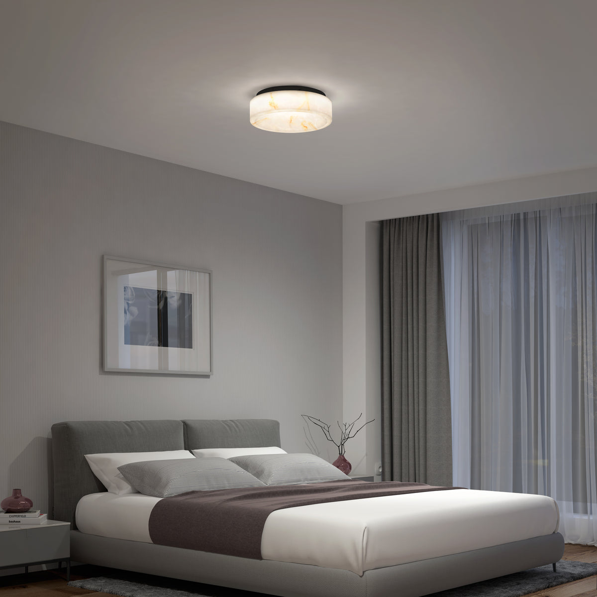 A modern bedroom with a gray upholstered bed, white bedding, a dark gray throw, nightstand, wall art, large window with sheer curtains, and an Artika Clifford 15 in. flush mount light softly illuminating the room.