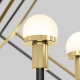 A close-up of a modern brass and black lamp with a frosted glass globe shade, set against a neutral background with blurred metallic lines.