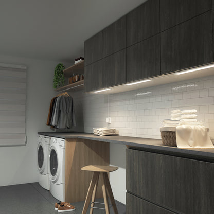 Modern laundry room with dark cabinets, washer/dryer, Artika Maestro under cabinet LED lights, folded towels, hanging clothes, and shelves.