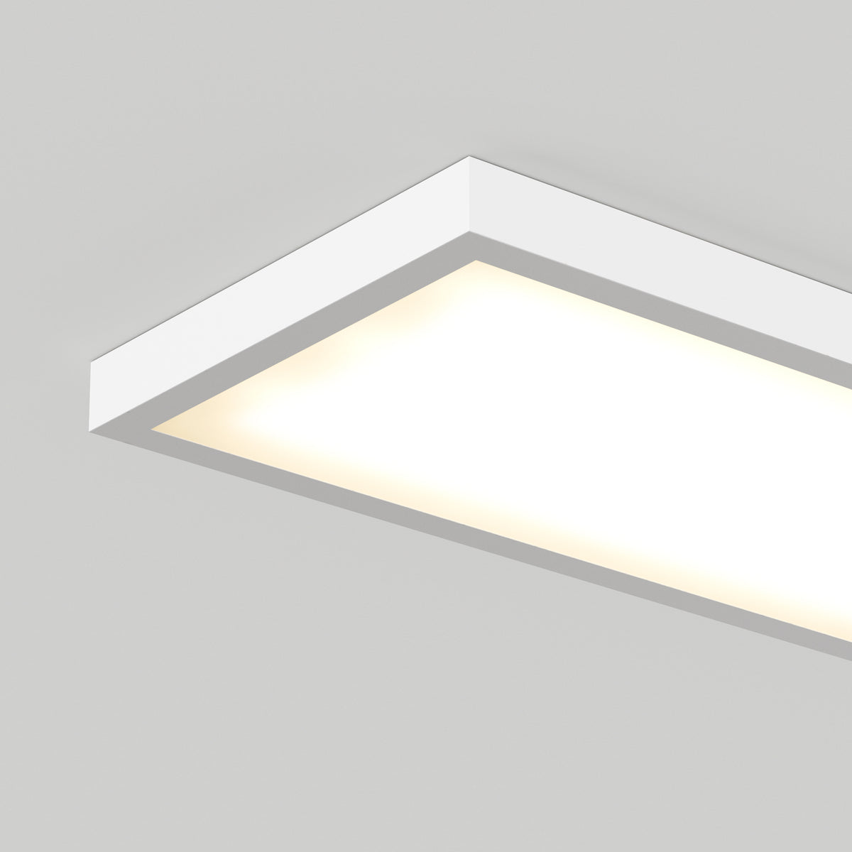 A rectangular, white, ceiling-mounted LED light fixture illuminated against a plain light gray ceiling.
