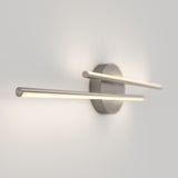 A modern wall light fixture with two horizontal, cylindrical LED bars extending from a round metallic base, mounted on a white wall. The fixture emits a soft, diffused glow.