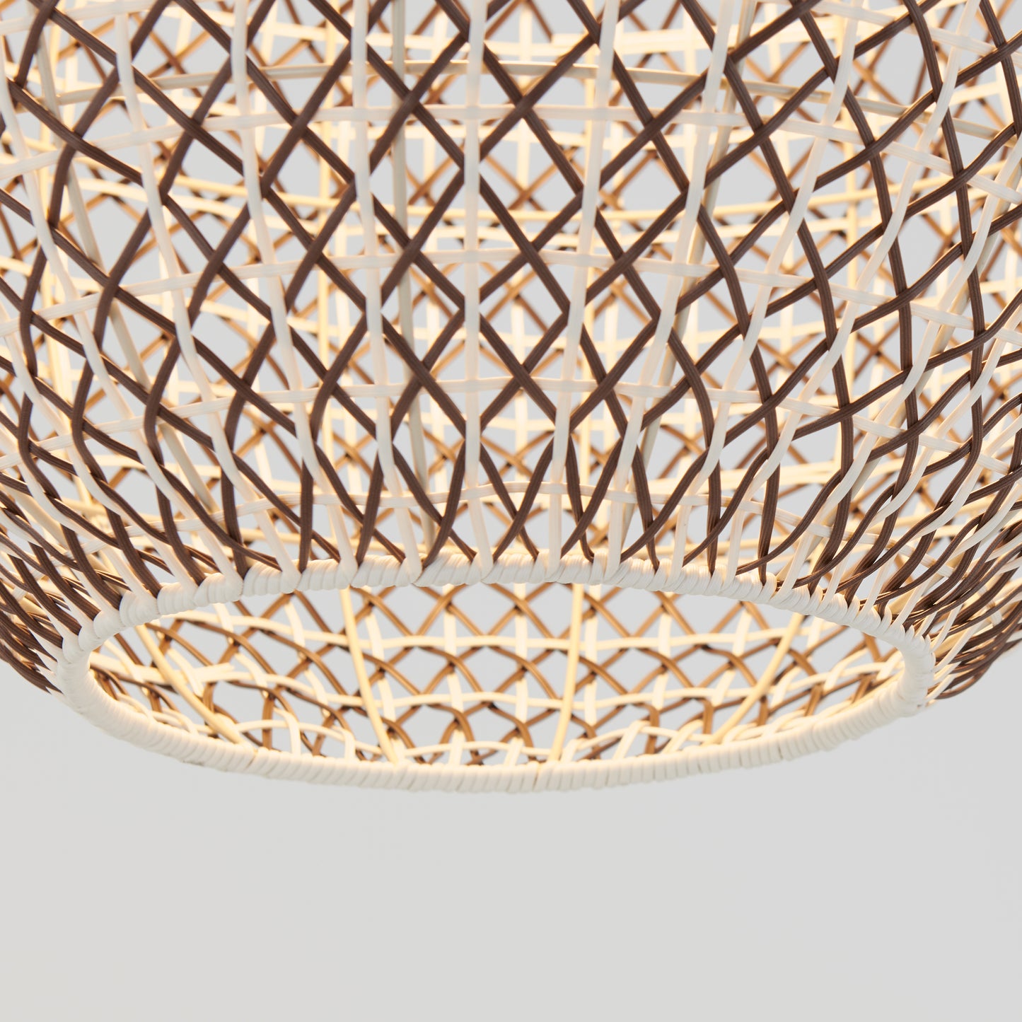 A close-up of the Artika Benson LED pendant light 5 CCT showcases its woven rattan geometric lattice shade, warmly illuminated from within, casting a glowing effect against a neutral background.