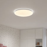 A round, modern ceiling light glows softly in a room with white walls featuring a subtle polka dot pattern. White cabinets and shelves, some holding a teddy bear and a letter R, are visible below.