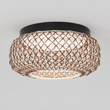 A round ceiling light with a woven rattan shade in a crisscross pattern, mounted on a dark circular base against a plain white ceiling.