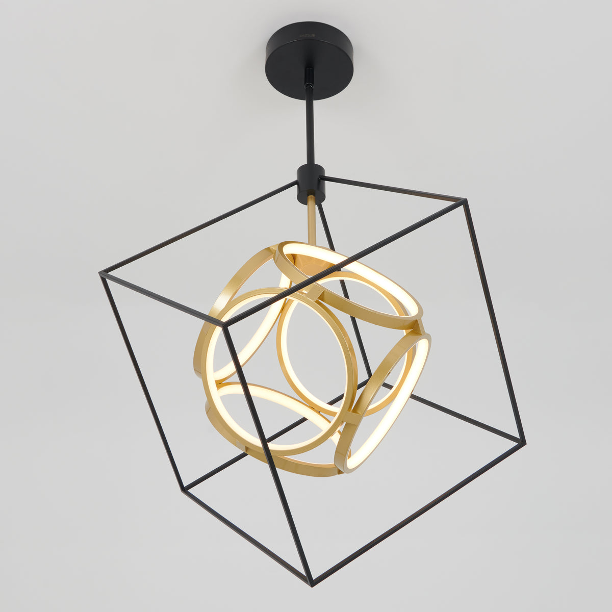 A modern ceiling light fixture features a glowing abstract gold shape suspended within a black wireframe cube, all mounted to the ceiling with a black base. The design is geometric and contemporary.