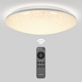 A modern round ceiling light emitting a warm glow is mounted on a white ceiling. Below it, a black remote control is displayed, showing several buttons and a wireless signal icon.