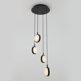 A modern ceiling light fixture with four hanging pendant lights, each featuring a circular design with textured, illuminated glass, suspended at different heights by black cords from a round black base.
