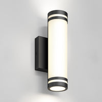 The Artika Bradley modern LED indoor-outdoor wall light 3 CCT features a black base and frosted white diffuser, mounted on a light gray wall, emitting soft upward and downward lighting.