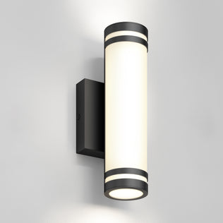 The Artika Bradley modern LED indoor-outdoor wall light 3 CCT features a black base and frosted white diffuser, mounted on a light gray wall, emitting soft upward and downward lighting.