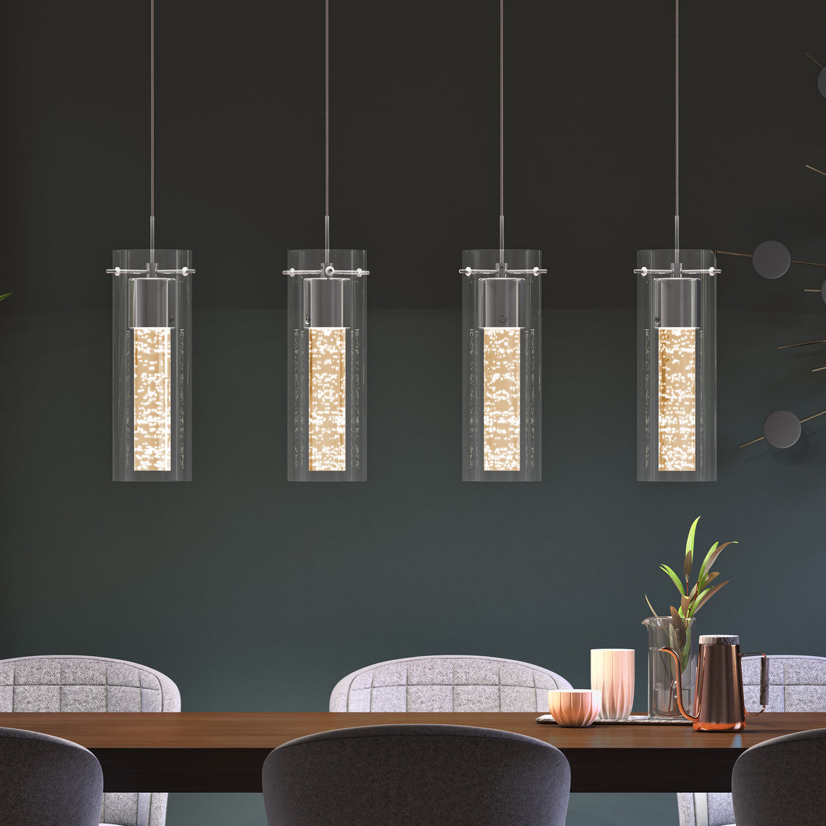 Four modern cylindrical pendant lights with textured glowing centers hang above a wooden dining table set with candles, a copper pitcher, and plants. The scene features gray upholstered chairs and a dark wall background.