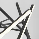 Close-up of a modern light fixture with intersecting black metal rods, each featuring a glowing white LED strip, against a plain light gray background.