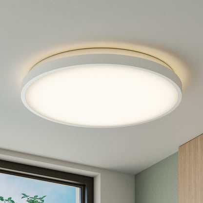 The Artika Isara 15 in. RGBIC LED Flush Mount lights up a bright room with a glimpse of window and cabinet in view.